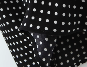 Detailed macro view of black and white polka dot fabric with smooth hem stitching