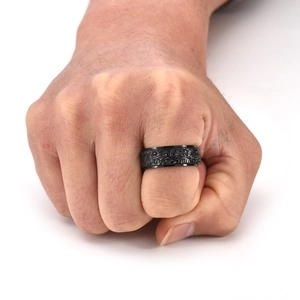 Gros plan d'une bague rotative en acier noir avec motifs de nuages sur une main d'homme