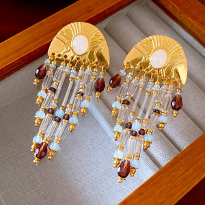 Détail de boucles d'oreilles vintage dorées avec perles rouges et glands sur velours