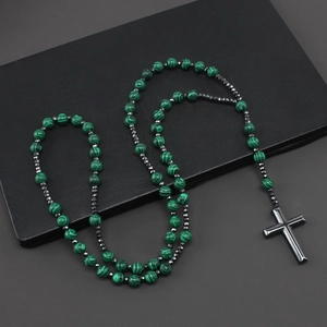 Green malachite beads necklace with metal cross pendant on dark background