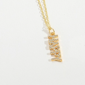 Close-up of golden necklace with HAPPY pendant featuring sparkling crystal embellishments