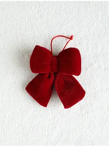 Macro shot of deep red velvet Christmas bow decoration on soft white textured fabric