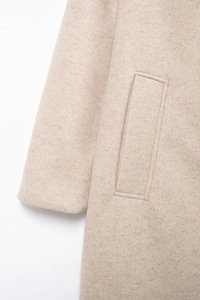 Détail de la texture en laine et des coutures sur la poche d'un manteau beige
