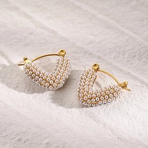 Macro view of V-shaped gold stainless steel earrings with inset white pearls