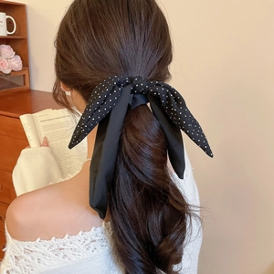 Detailed view of a black polka dot chiffon bow hair tie with long flowing ribbons