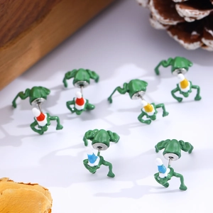 Creative green frog stud earrings with colorful Christmas hats on natural wooden stands
