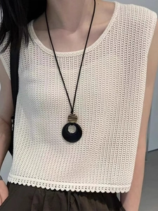 Close-up of faux agate circle pendant necklace styled with a beige crochet top