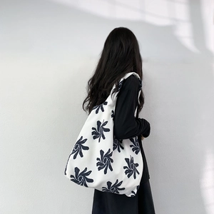 Detailed back view of a white canvas tote bag with blue floral print on female model
