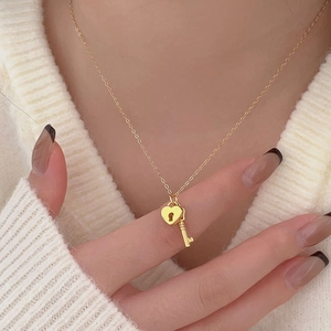 Detail of a 925 silver heart lock and key pendant necklace on a gold O-chain