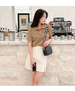 Chic black quilted crossbody bag styled with a brown knit polo shirt and beige midi skirt