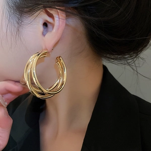 Detailed view of triple-layered golden hoop earrings worn for a luxury fashion look