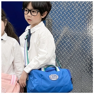 Close-up of blue nylon dance bag with green and white striped handles and logo patch