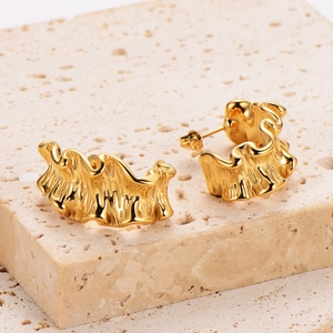 Modern 18k gold plated wave earrings with pleated texture on beige stone surface