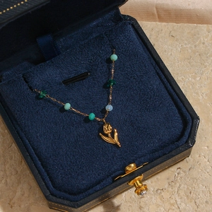 Collier tulipe doré avec perles colorées présenté dans un écrin de velours bleu marine