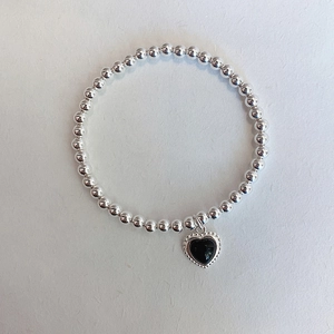 French vintage silver beaded bracelet with a black heart pendant on a gray background