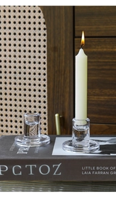 Macro shot of elegant clear glass candle holders with a lit candle on a dark book