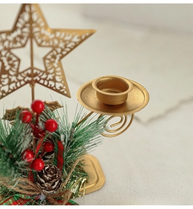 Close-up of gold Christmas candle holder with star cutouts, pine cones and red berries