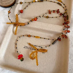 Vintage beaded necklace with bow, dragonfly element and red mushroom pendant on paper tray