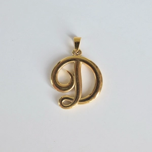Vue macro d'un pendentif en acier inoxydable doré 18K avec la lettre D en cursive