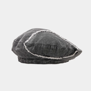 Detailed texture of charcoal grey washed denim beret with distressed frayed edges