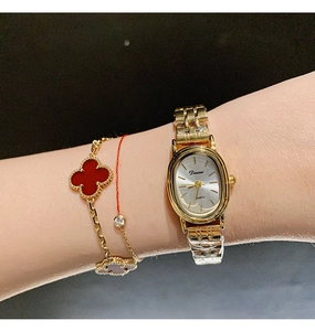 Detail of elegant gold quartz watch with oval white dial worn on female wrist
