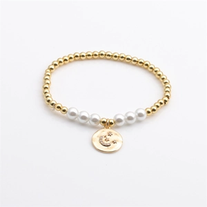 Bracelet extensible en perles dorées avec perles blanches et pendentif lune et étoile