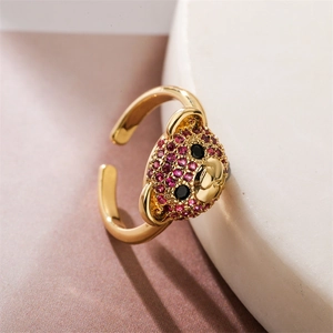 Macro detail of adjustable gold bear ring with pink zircon pave setting on marble base
