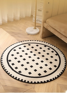 Detail of round cream woven rug with black geometric pattern on wooden floor