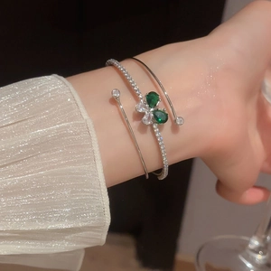 Dettaglio di bracciali rigidi argento con pietre a goccia verde smeraldo e zirconi
