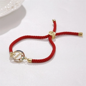 Detailed shot of red woven mama bracelet with colorful zircons and gold adjustable clasp