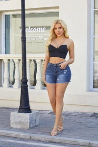 Detail of high-waisted distressed denim shorts with fringe and rhinestone chain top