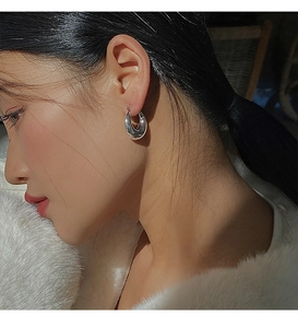 Gros plan d'une boucle d'oreille goutte en argent poli montrant un éclat métallique
