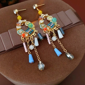 Gros plan de boucles d'oreilles bohèmes à pompons avec cristaux colorés et perles