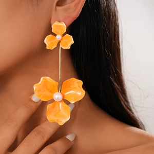 Close-up of bohemian orange floral resin earrings with faux pearls on model