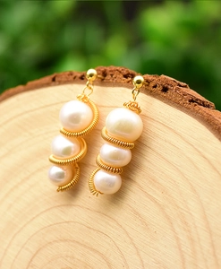 Macro detail of natural white pearls wrapped in gold wire on a wooden display stand