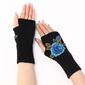 Detail of black knit fingerless gloves featuring blue rose embroidery on a white background