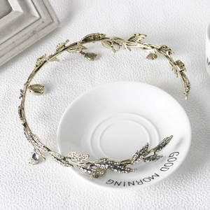 Detail of a golden leaf bridal headpiece with sparkling rhinestones on a ceramic dish