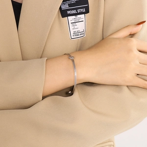 Gros plan d'un bracelet jonc argenté avec nœud minimaliste porté par un mannequin