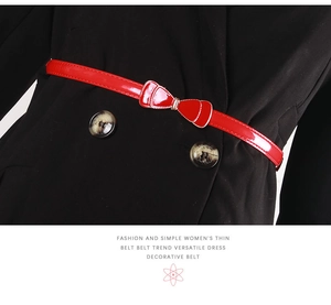 Detail of red patent leather slim belt with bow buckle on a black wool coat