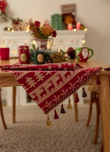 Detail of red Christmas table runner with golden snowflake deer patterns and tassels