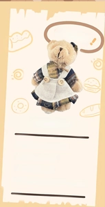 Detail of plush bear keychain wearing a vintage plaid dress and apron as a bag charm