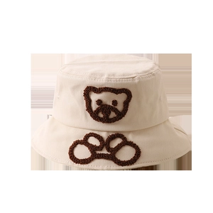 Détail de la broderie ours en serviette sur un chapeau bob en coton beige pour bébé