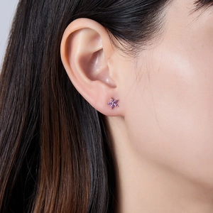 Close-up of small purple flower stud earrings with marquise zircon petals on ear