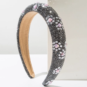 Macro detail of headband featuring dark rhinestones and pink heart-shaped crystal accents