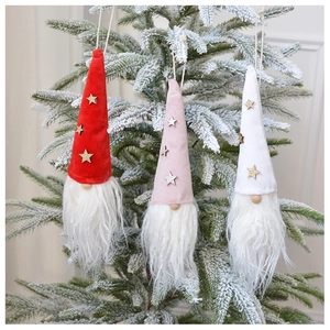 Close-up of plush Christmas gnome ornaments hanging on snowy tree branches