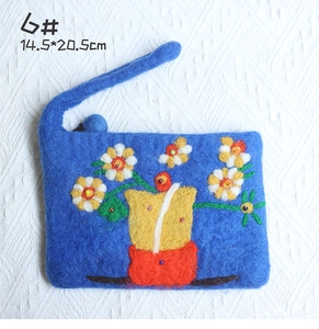Detail of blue wool felt bag with handcrafted daisy embroidery and floral vase pattern