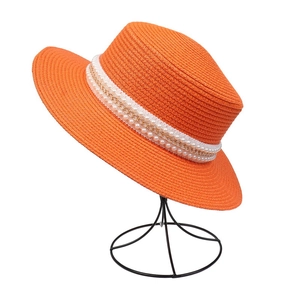 Detail of orange straw hat with elegant pearl and gold chain decorative band decoration