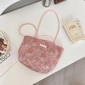 Détail du sac cabas en toile fleurie avec anses roses et étiquette de marque Sozakka brodée