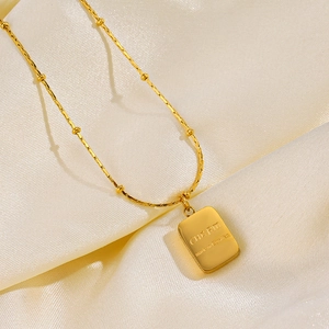18K gold plated stainless steel necklace with charm pendant on beige silk fabric