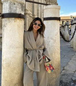 Detail of khaki linen kimono top and wide leg trousers set worn in an outdoor street setting
